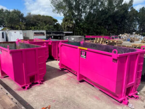 different sizes of Wasteline Solutions pink dumpsters in yard