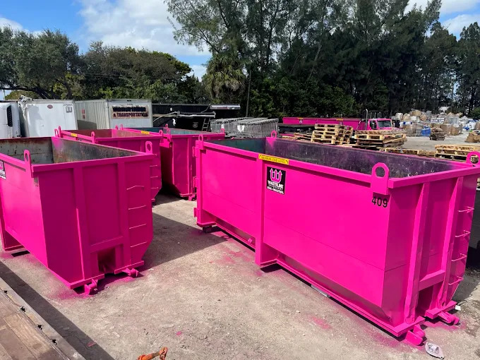 different sizes of Wasteline Solutions pink dumpsters in yard