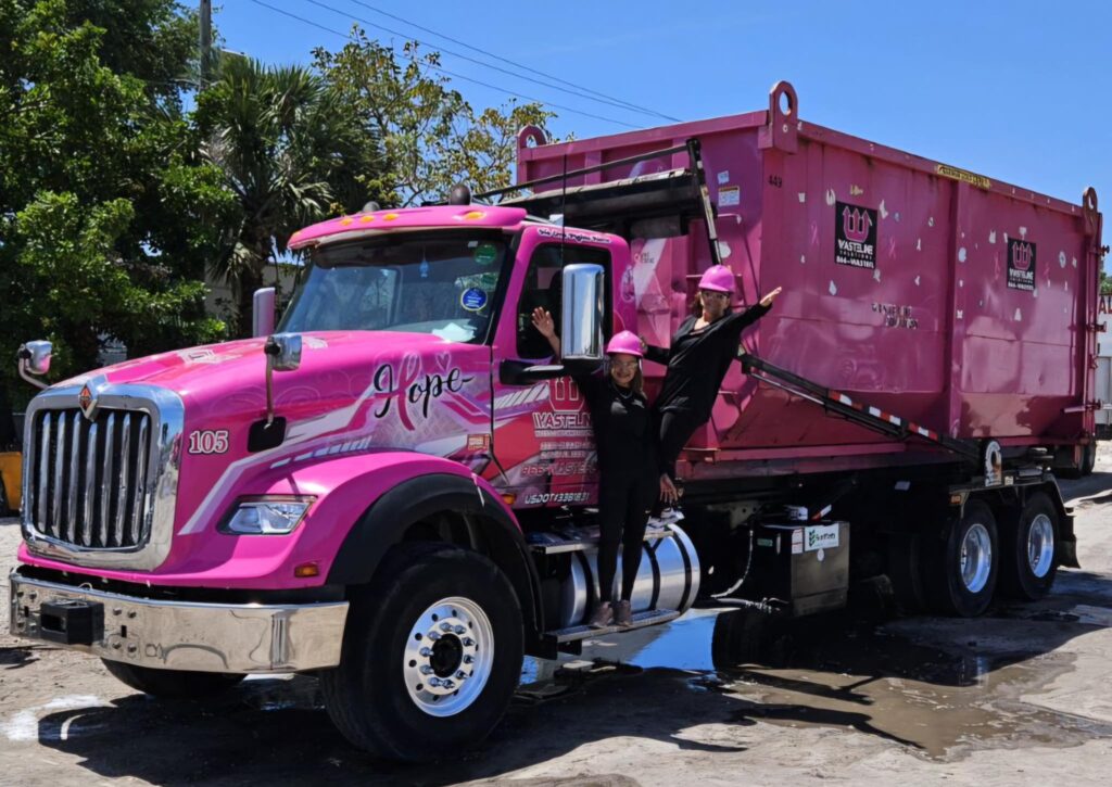 Mrs. Tina and Oriana standing on pink dumpster truck from Wasteline Solutions