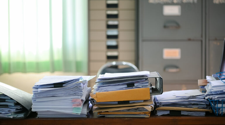papers on cluttered office desk - Wasteline Blog
