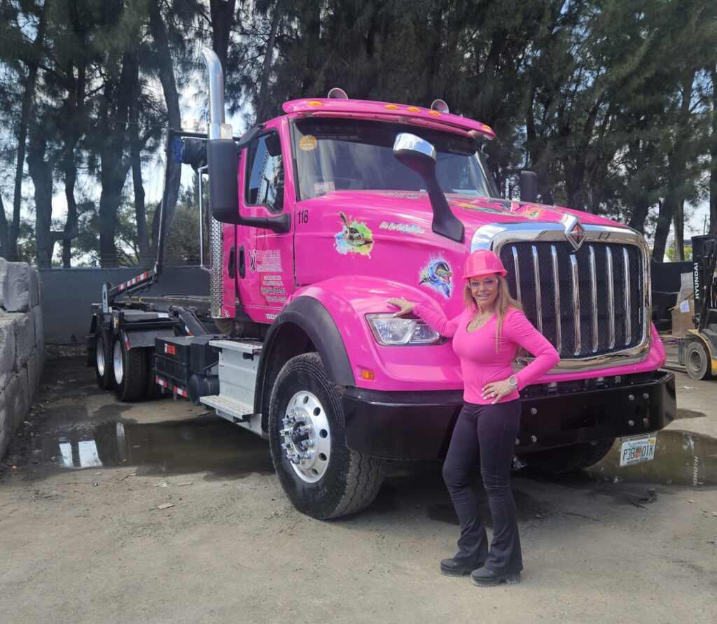 Mrs. Tina standing in front of pink Wasteline Solutions truck